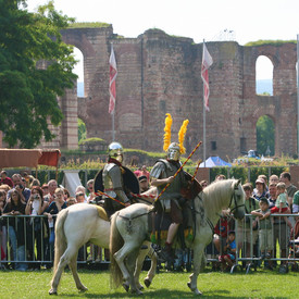 Viele Menschen stehen vor den Kaiserthermen und schauen Ritterspielen zu