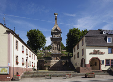 Große, mehrstöckige Säule mit abgebildeten Szenen aus dem Leben von (Tuch-)Händlern